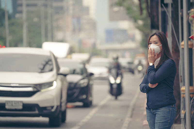 Lady with a face mask on beside a busy road